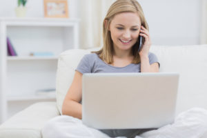 young-girl-talks-on-the-phone-and-types-on-her-laptop